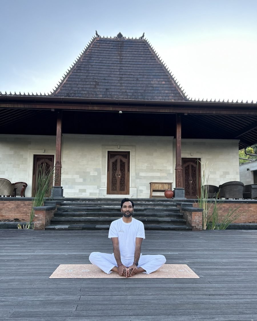 Mayank Rajput seated in meditation at a traditional pavilion, embodying Soul Light Yoga's roots